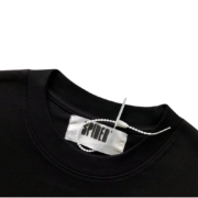 Close-up of the Sp5der Jeffery Heavyweight Black Tee neck tag detail showing branding and clothing label construction.