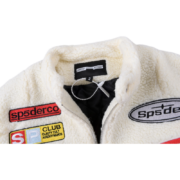 Detail view of the Sp5der Wor1dwide 555555 Hunters Sherpa Jacket, highlighting the neck tag and patterned chest patches.