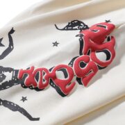 Detailed close-up view of the Sp5der x Mariah the Scientist cream sweatpants featuring a bold red scorpion graphic print.