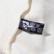 Close-up of the Sp5der x Mariah the Scientist Scorpion Sweatpants brand tag on premium cream fabric material.