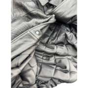 Close-up of the SP5DER leather jacket featuring a debossed spider web pattern, studded accents, and quilted lining.