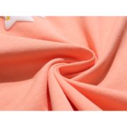 Close-up view of a premium peach Sp5der Print t-shirt showing soft cotton fabric texture and a star graphic detail