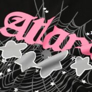 Close-up graphic of the Sp5der Young Thug Atlanta t-shirt featuring pink lettering, grey clouds, and a spider web design.
