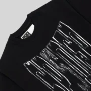 A close-up view of the black Sp5der Diffused Collegiate Tee showing the textured white graphic and neck label details