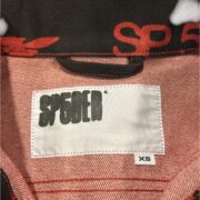 Close-up of the Sp5der 5ex AOP denim trucker jacket, showcasing the branded inner neck label and signature red print.