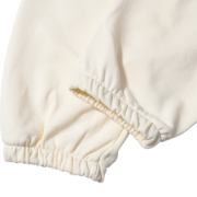 Close-up of the cream-colored Sp5der x Mariah the Scientist Scorpion sweatpants, focusing on the elasticated hem detail.