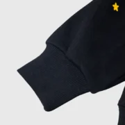Black Sp5der Atlanta Star-Print Hoodie showing close-up of the ribbed cuff detail and premium fleece construction.