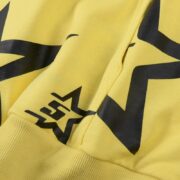 Detail of the vibrant yellow Sp5der 5Star Hoodie featuring the iconic black star print and premium cotton fabric.