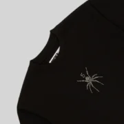 Close-up view of the black Sp5der TM rhinestone tee showing the signature crystal-embellished spider logo graphic.
