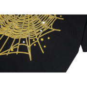 A close-up view of the SP5DER web print design on a black Gothic punk t-shirt with golden and white star details.