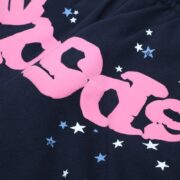 Close-up of Sp5der Atlanta blue sweatpants featuring a high-quality pink graphic logo print with small star details.