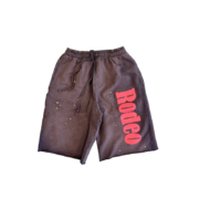 Front view of the Sp5der x Cactus Jack Rodeo shorts featuring pink lettering and star accents on dark fabric.