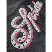 Premium black SP5DER leather jacket featuring an intricate debossed web pattern and a large studded pink script logo.