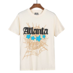 Sp5der Atlanta graphic t-shirt in cream featuring a signature web print and blue stars, front view for streetwear fans.