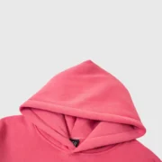 Detail view of the vibrant pink Sp5der Legacy Hoodie, highlighting the premium cotton-blend fabric and hood.