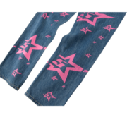 Sp5der 5Star Vintage 501 denim jeans featuring a bold pink star print pattern on high-quality distressed blue denim fabric.