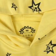 Sp5der 5Star Hoodie in yellow featuring a close-up of the brand neck label and signature black star print pattern
