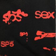 Detailed close-up of the Sp5der Sex AOP sweatpants featuring a bold red all-over graphic print on soft black fabric.
