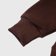 Close-up view of the ribbed sleeve cuff detail on the authentic Sp5der OG Web V2 Hoodie in a rich brown colorway.