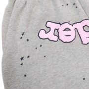 Close-up of Sp5der OG Web Logo sweat shorts in grey French Terry cotton with pink graphic lettering and black stars.