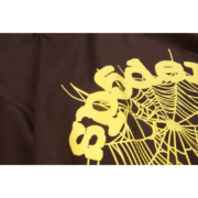 Close up of the Sp5der OG Web Tee in brown featuring the brand's signature yellow spider web graphic print design.