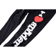 Close-up view of the Sp5der Souvenir SP5 black sweatpants featuring a prominent red heart and white graphic text print.