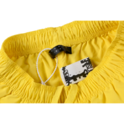 A detailed close-up showing the interior brand tag and labels inside the bright yellow Sp5der OG Web Double Layer Shorts.