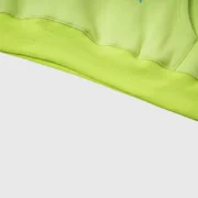Close-up view of the vibrant green cotton fabric and ribbed hem detail on the Sp5der OG Web V2 streetwear pullover hoodie.