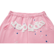 Front view of pink Sp5der Atlanta unisex sweatpants with white logo lettering, distressed details, and star print.