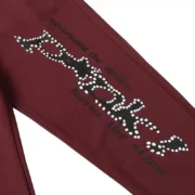 Detail view of the brown Sp5der P*nk sweatpants featuring high-quality distressed branding and graphic print design.