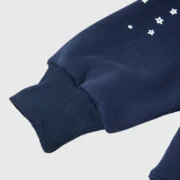 Close-up of the navy blue sleeve on the Sp5der OG Web Hoodie featuring the signature star logo print and ribbed cuff.