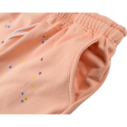 Close-up view of the Sp5der Bellini sweatpants featuring a vibrant peach hue, elastic waistband, and star print detail.