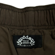 Close-up view of the brand tag on a pair of Sp5der OG Web double layer streetwear shorts showing size M detail.