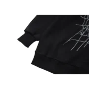 Detailed view of the black Sp5der Web Hoodie featuring iconic spider web graphic print on high-quality fabric.