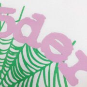 Close-up view of the Sp5der OG Web T-shirt featuring a green spider web graphic and pink logo text on a white cotton base.