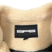 Close-up of the Sp5der Worldwide Hunters Sherpa Moto Jacket interior showing the branded black logo neck tag on fleece.
