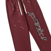 Front view of the brown Sp5der P*nk sweatpants featuring white rhinestone graphic detailing and star accents.