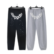 Front view of SP5DER black and gray OG web sweatpants hanging on hangers, featuring distressed logo and star details.