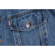 Close-up view of the branded pocket button and red logo tag on the premium SP5DER Worldwide Denim Jacket.