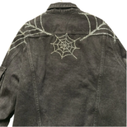 Sp5der Worldwide black denim jacket featuring a signature rhinestone crystal spider web motif on the back yoke design.