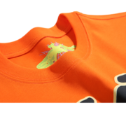 Close-up view of the collar and interior branding on an orange Sp5der Worldwide Star Beluga T-shirt with graphic details.