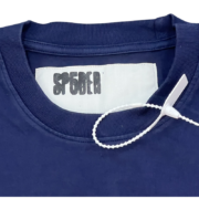 Close-up of the inner neck label on a dark blue Sp5der 5 Baby Tee featuring the iconic brand logo and white hang tag.