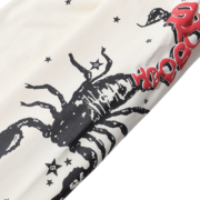 Cream Sp5der x Mariah the Scientist sweatpants featuring a black scorpion graphic and red star-detailed print design.