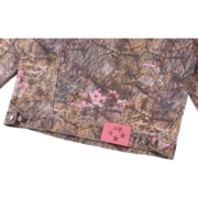Close-up view of the Real Tree Camo pattern on the Sp5der Trucker Jacket, showing the rugged fabric and pink branding tag.