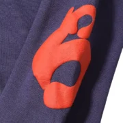 Close up of the high-quality vibrant orange print detail on the navy blue Sp5der Beluga sweatpants fabric.