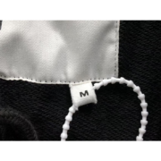 Close-up view of a size M tag detail on the Sp5der Sex AOP Sweatpants, showcasing the brand's premium craftsmanship.