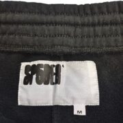 Close-up of the Sp5der Black OG Logo Embroidered Sweatshorts size tag on the inner waistband of the garment.