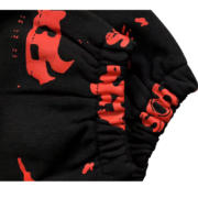 Closeup view of the Sp5der Sex AOP sweatpants featuring a bold red print on high-quality black fabric streetwear.