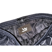 Close-up of the elastic waistband and brand tag on the black Sp5der Lost Files web shorts with a hanging size label.