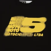 Front view of the black Sp5der Moto 5 Tee featuring a bold yellow spray paint graphic print on the cotton fabric.
